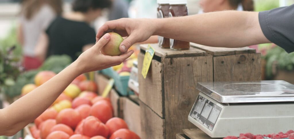 Farmers market kids and seller sharing apple