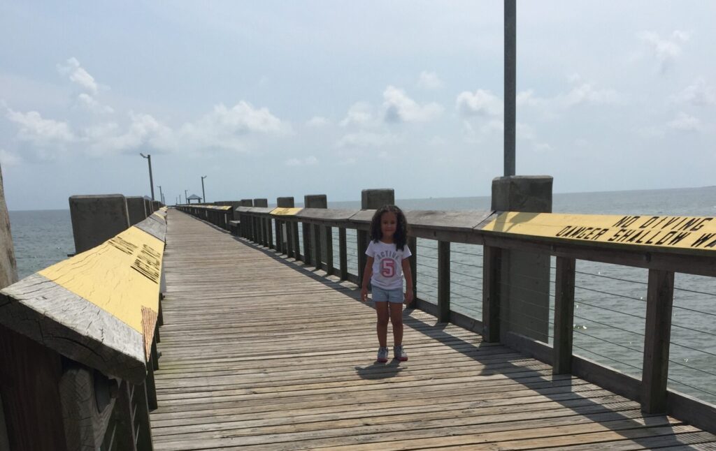 Child standing on a wooden boardwalk in Pascagoula.