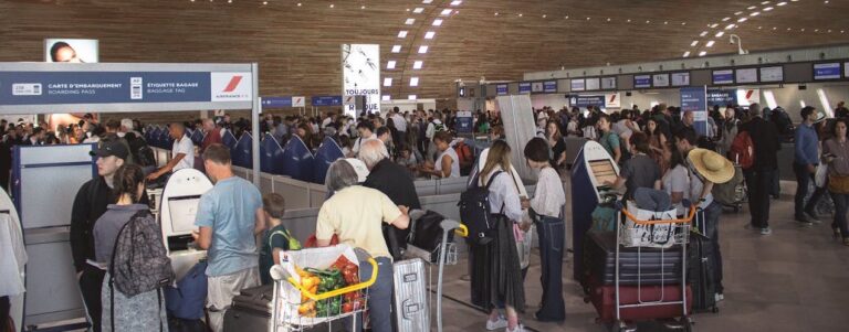 Crowded airport terminal with passengers waiting in line at check-in counters