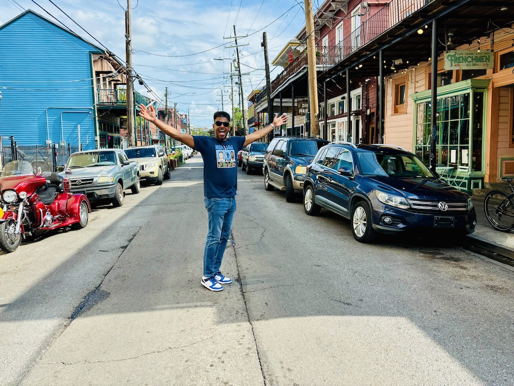 Man standing with arms outstretched on Frenchmen Street in New Orleans.