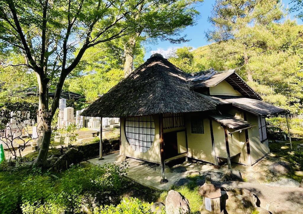 Historic Japanese tea house surrounded by lush greenery.