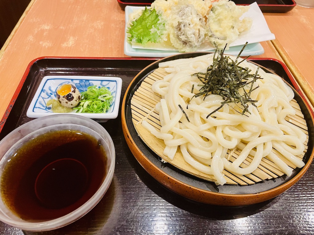 Traditional Japanese udon meal with dipping sauce and tempura.