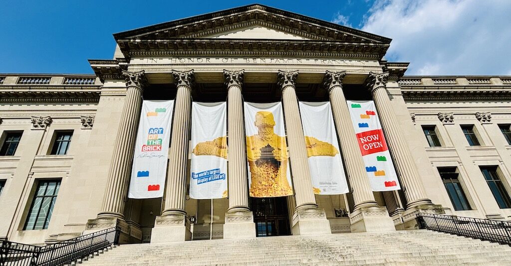 Exterior view of the Franklin Institute, a STEM museum in Philadelphia, showcasing the grand staircase and columns with exhibition banners.