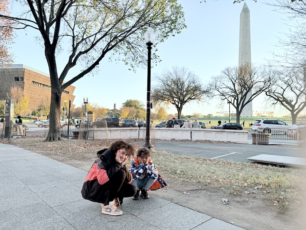 Siblings enjoying the National Mall with the Washington Monument in the background on their family-friendly D.C. itinerary.